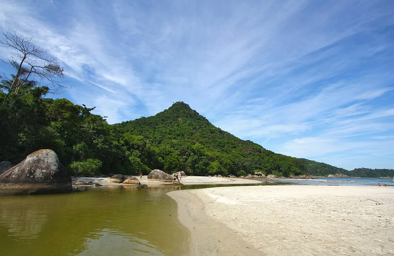 A praia longa de Dois Rios, com o mar calmo, a areia vazia e o morro pontudo coberto de mata ao fundo.