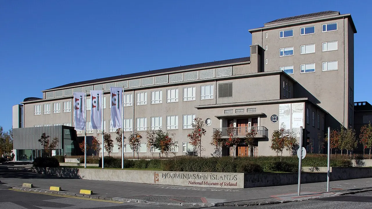 Prédio do Museu Nacional da Islândia, em Reykjavík, comprido e claro, com banners azuis na fachada.