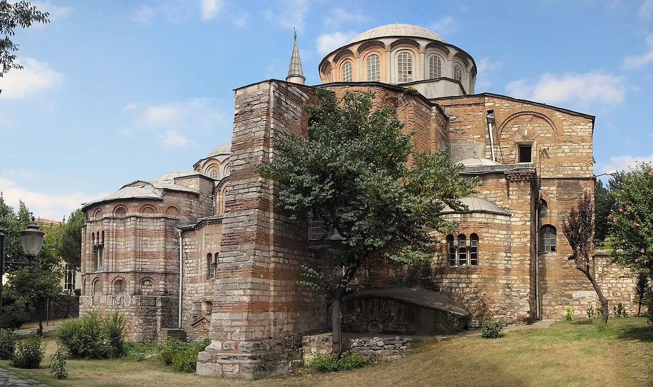 Igreja de Chora, em Istambul, de faixas de tijolo e pedra, com cúpulas baixas e uma árvore à frente.