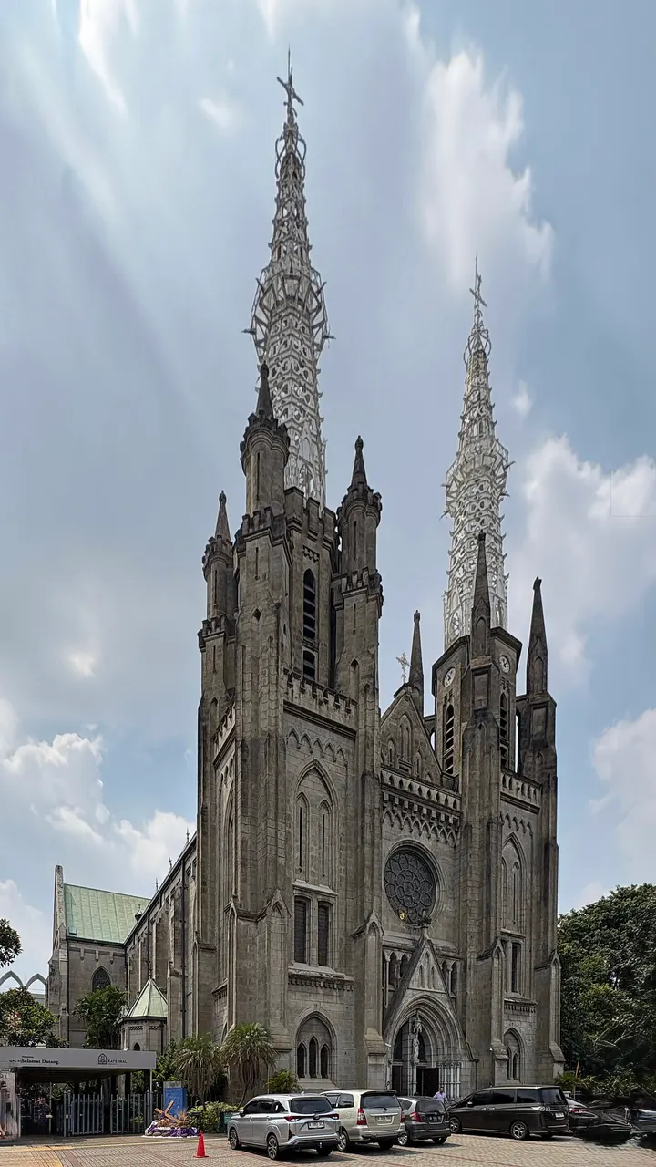 Igreja de tijolo escuro com duas torres altas e pontudas e rosácea central.