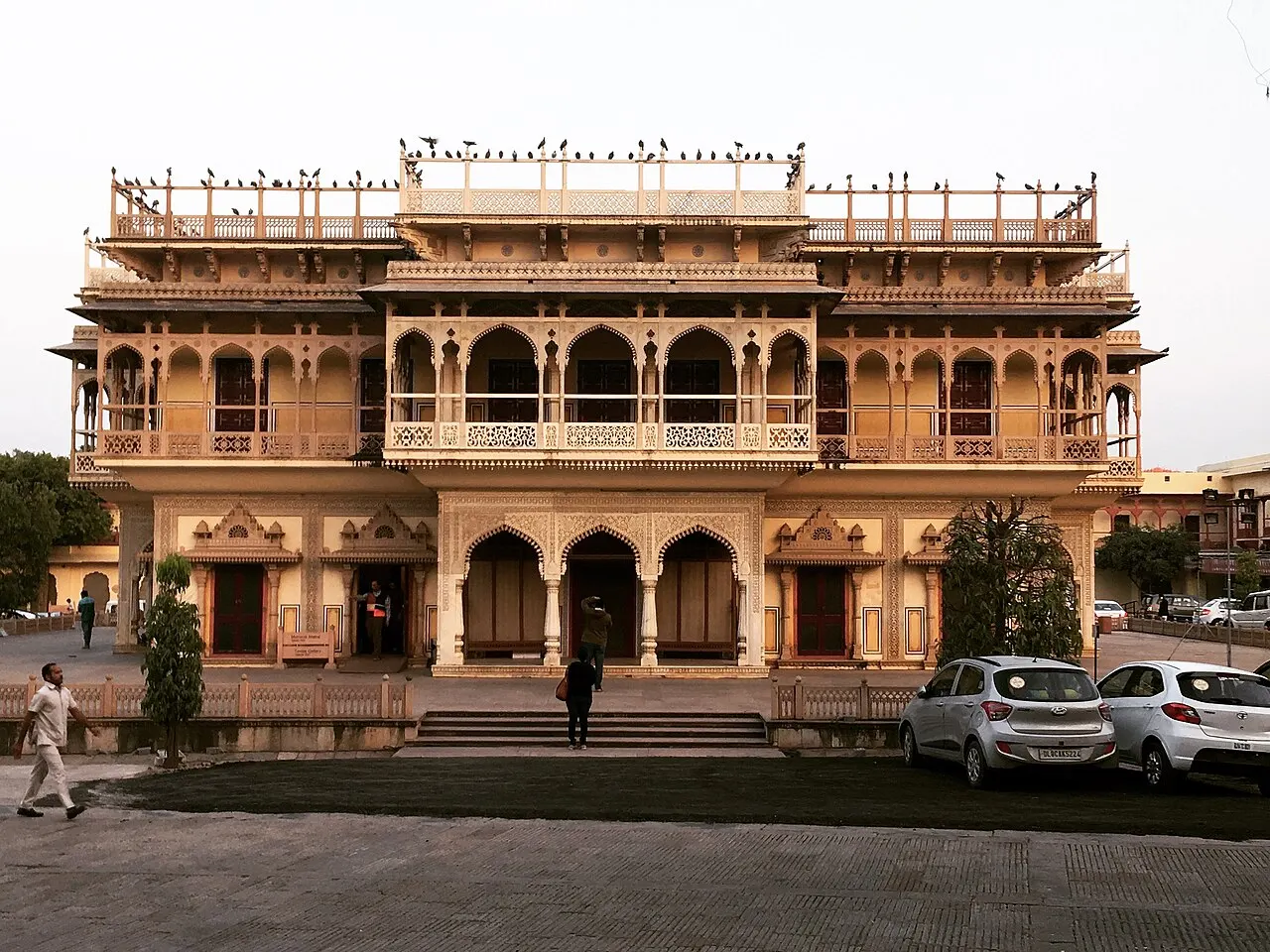 Fachada de palácio em tons de rosa e creme, com fileiras de varandas em arco e uma cúpula ao centro.