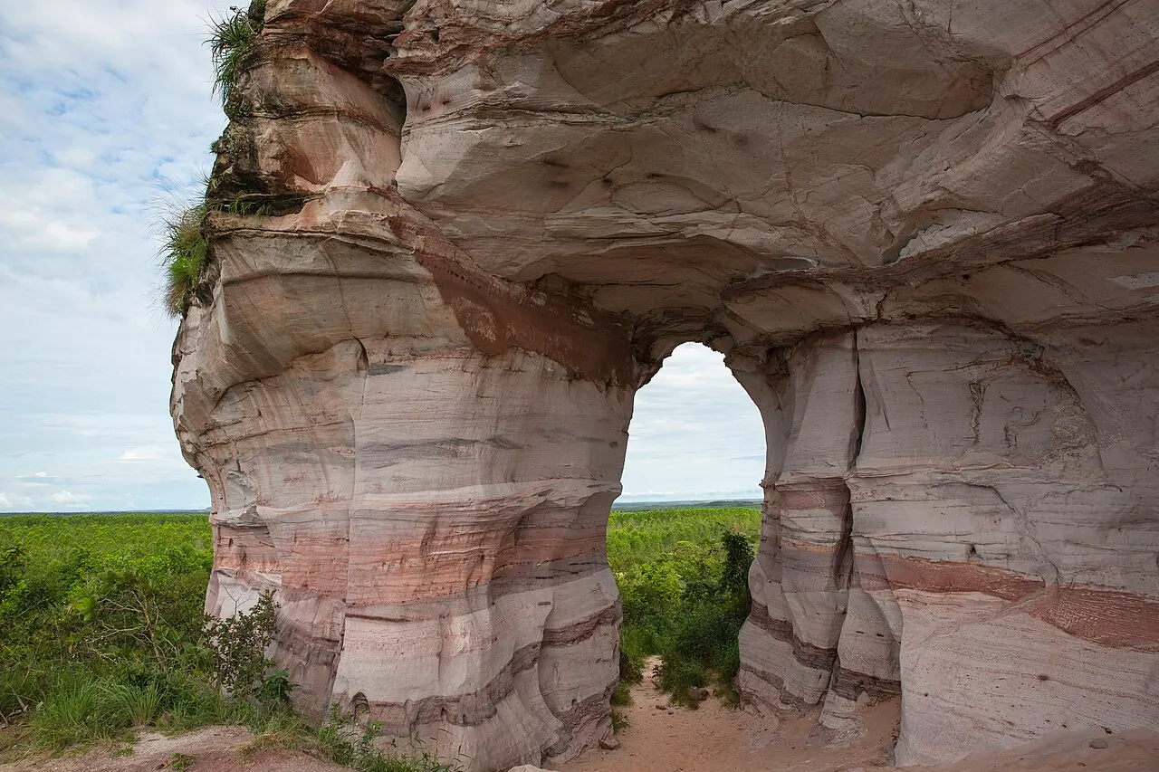 Os arcos de arenito claro e rosado da Pedra Furada, com o cerrado visto através das aberturas.