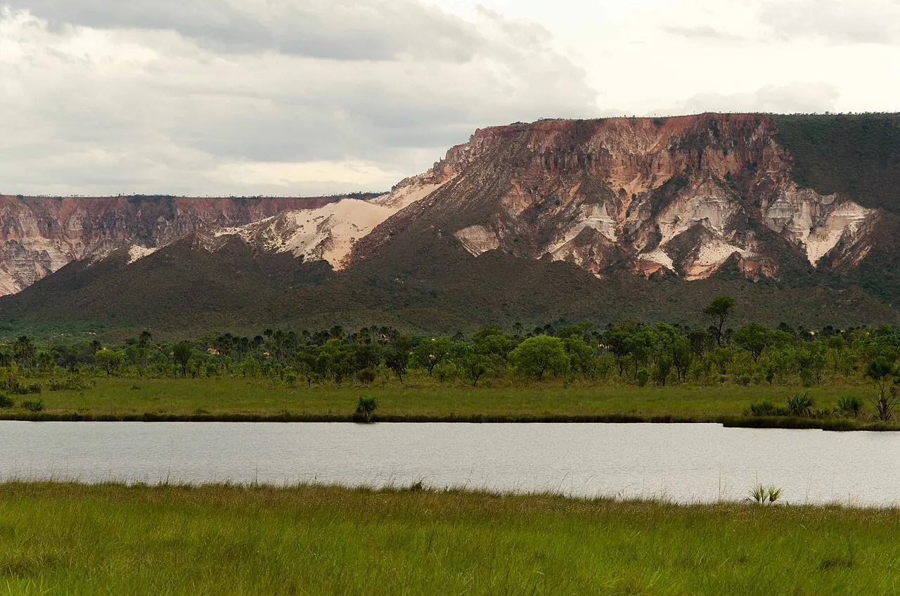 O paredão claro e avermelhado da Serra do Espírito Santo erguendo-se sobre o cerrado, com uma lagoa em primeiro plano.