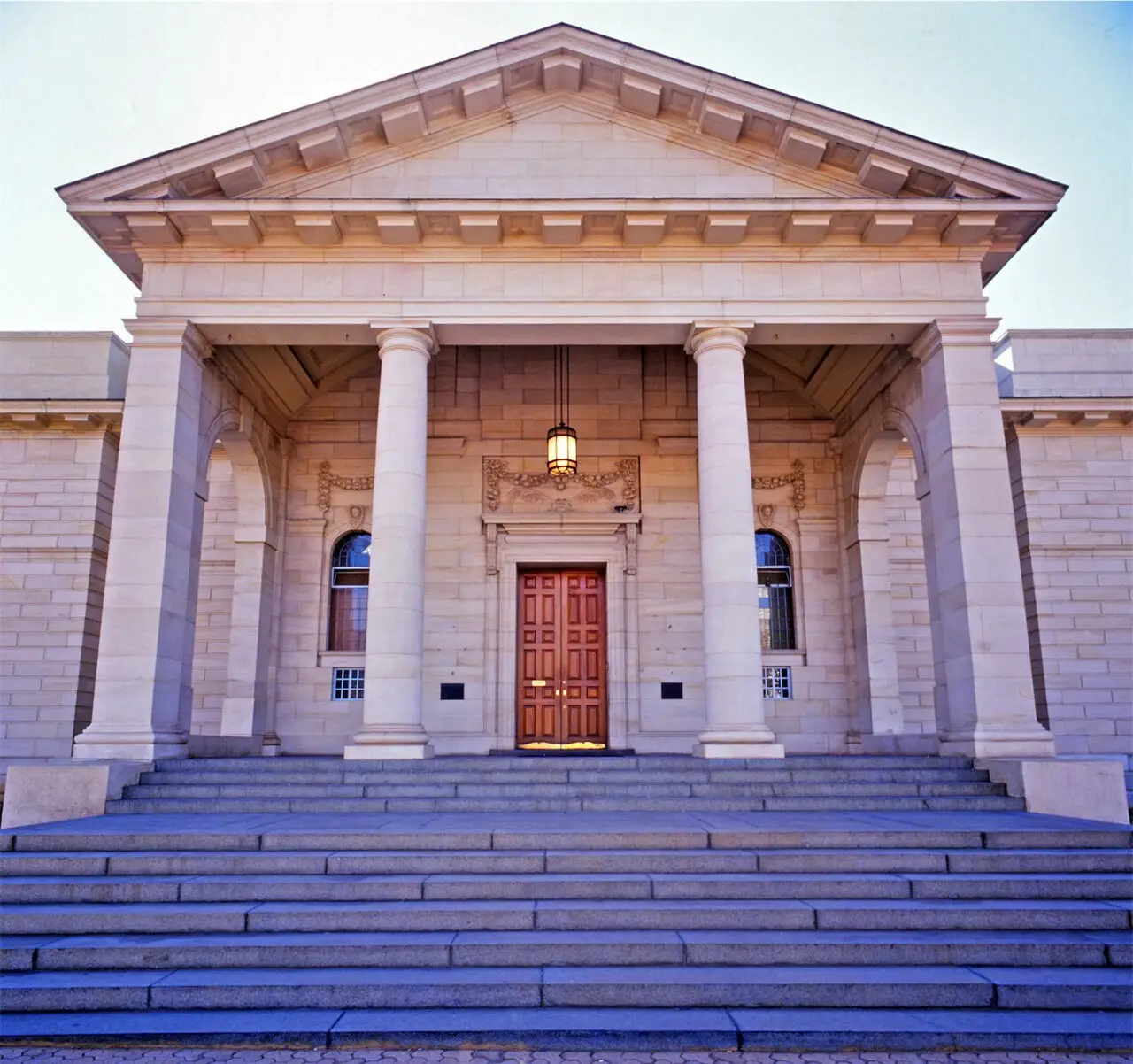 Fachada da Johannesburg Art Gallery, com pórtico de quatro colunas, frontão triangular e porta de madeira no alto da escadaria.