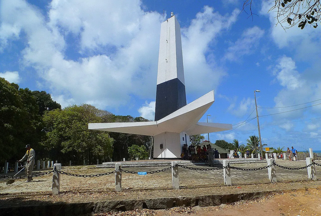 O Farol do Cabo Branco, de concreto branco e preto, com as abas em forma de folha, sob céu azul com nuvens.