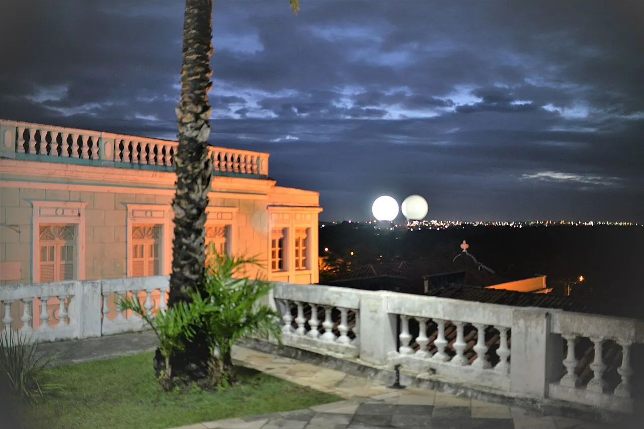 O casarão rosado do Hotel Globo ao anoitecer, com a balaustrada do terraço e os postes acesos.