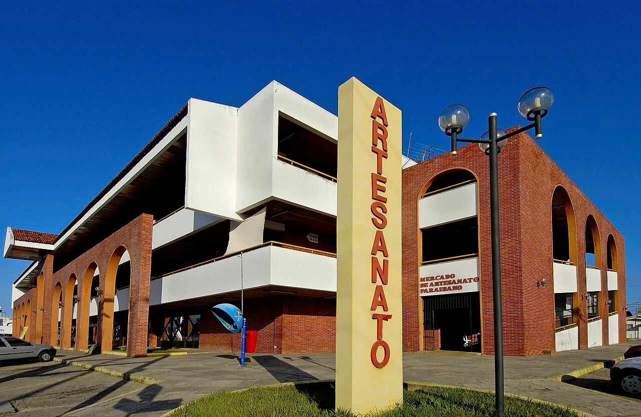 O prédio do Mercado de Artesanato Paraibano, de tijolo e concreto branco, com a placa vertical «Artesanato» na frente.