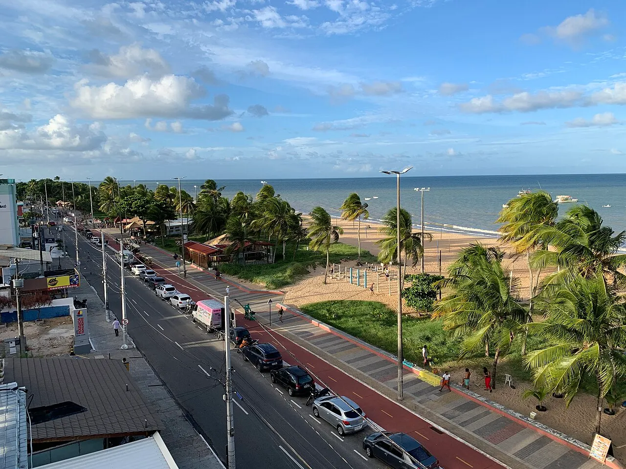 A orla de Tambaú vista do alto, com a avenida, os coqueiros do calçadão e o mar calmo.