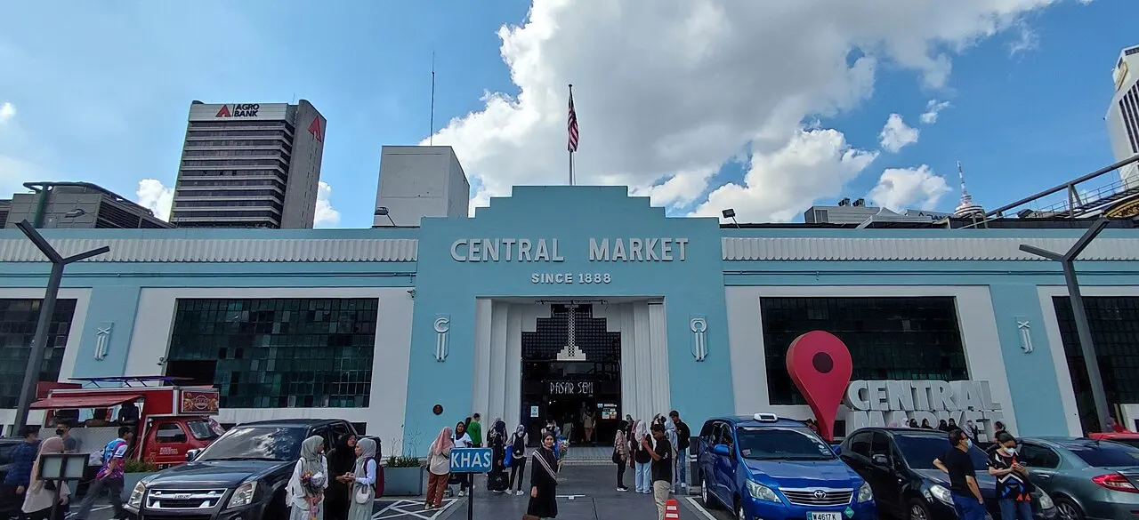 Fachada azul do Central Market, com o nome na entrada, carros na frente e pessoas na calçada.