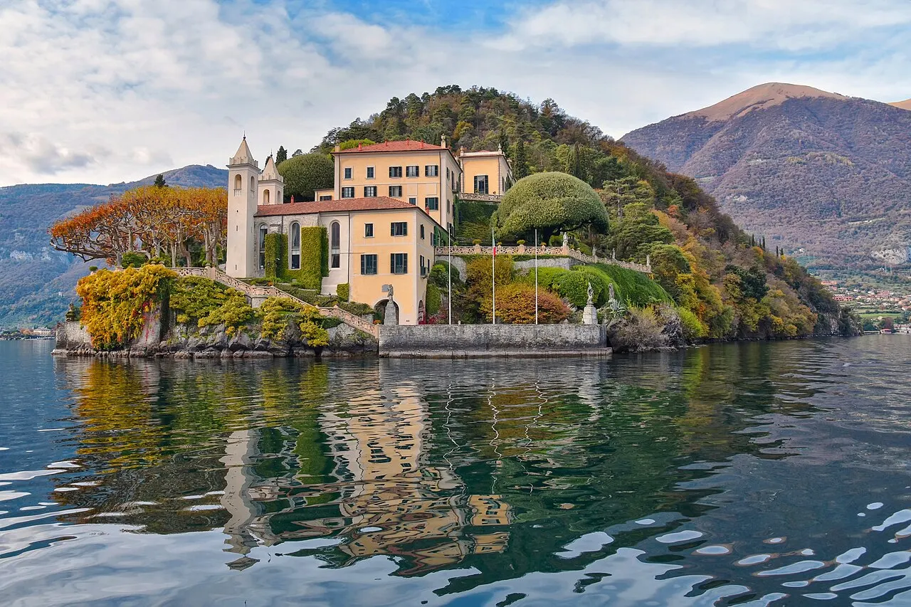 A Villa del Balbianello no fim de uma península arborizada, com a torre, a loggia e o jardim em tons de outono refletidos no lago.