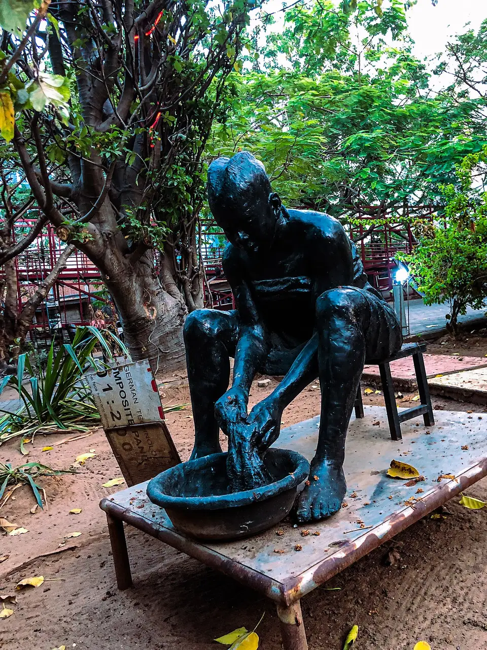Escultura azul de uma figura sentada num banco, no Freedom Park, em Lagos, entre a vegetação.