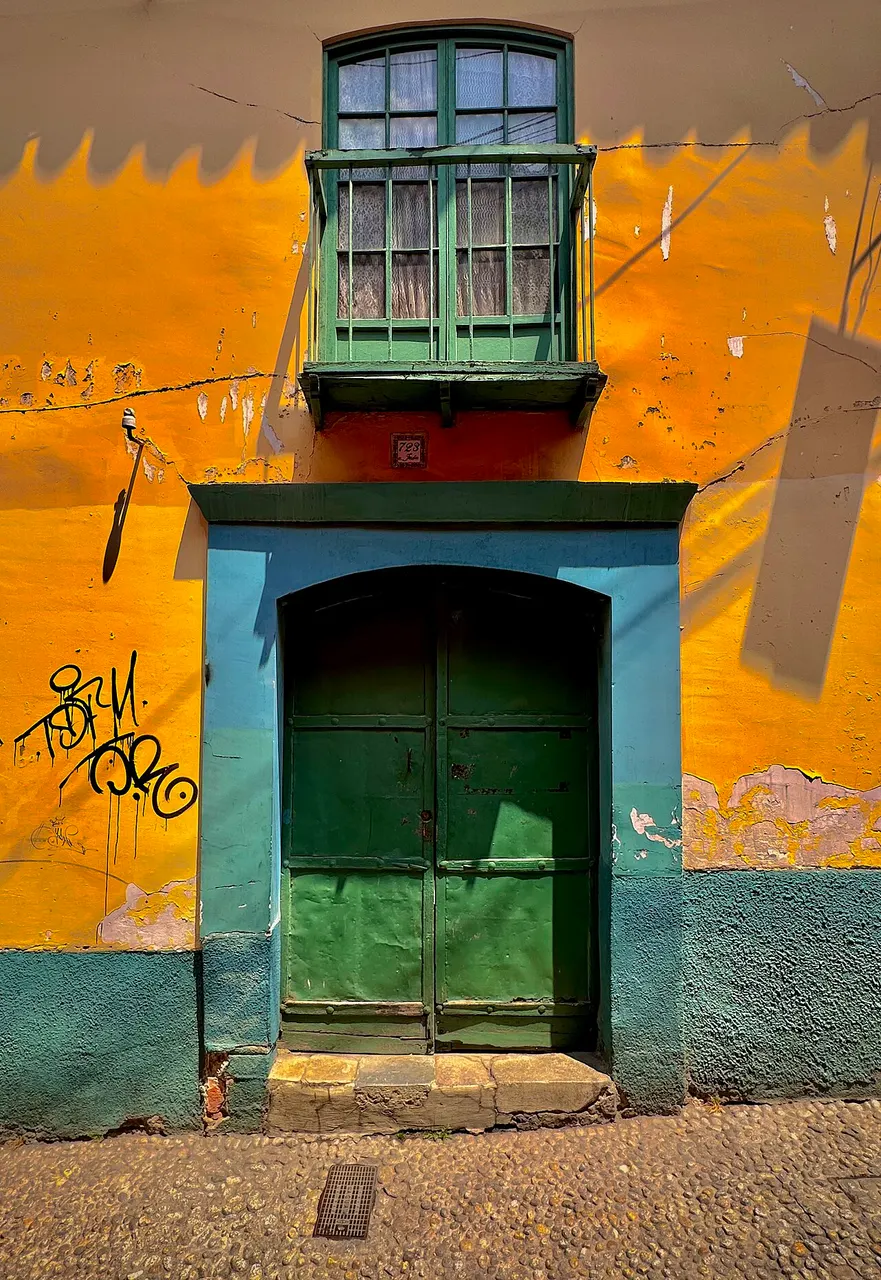Portal de uma casa colonial da Calle Jaén, com porta verde e sacada de madeira.