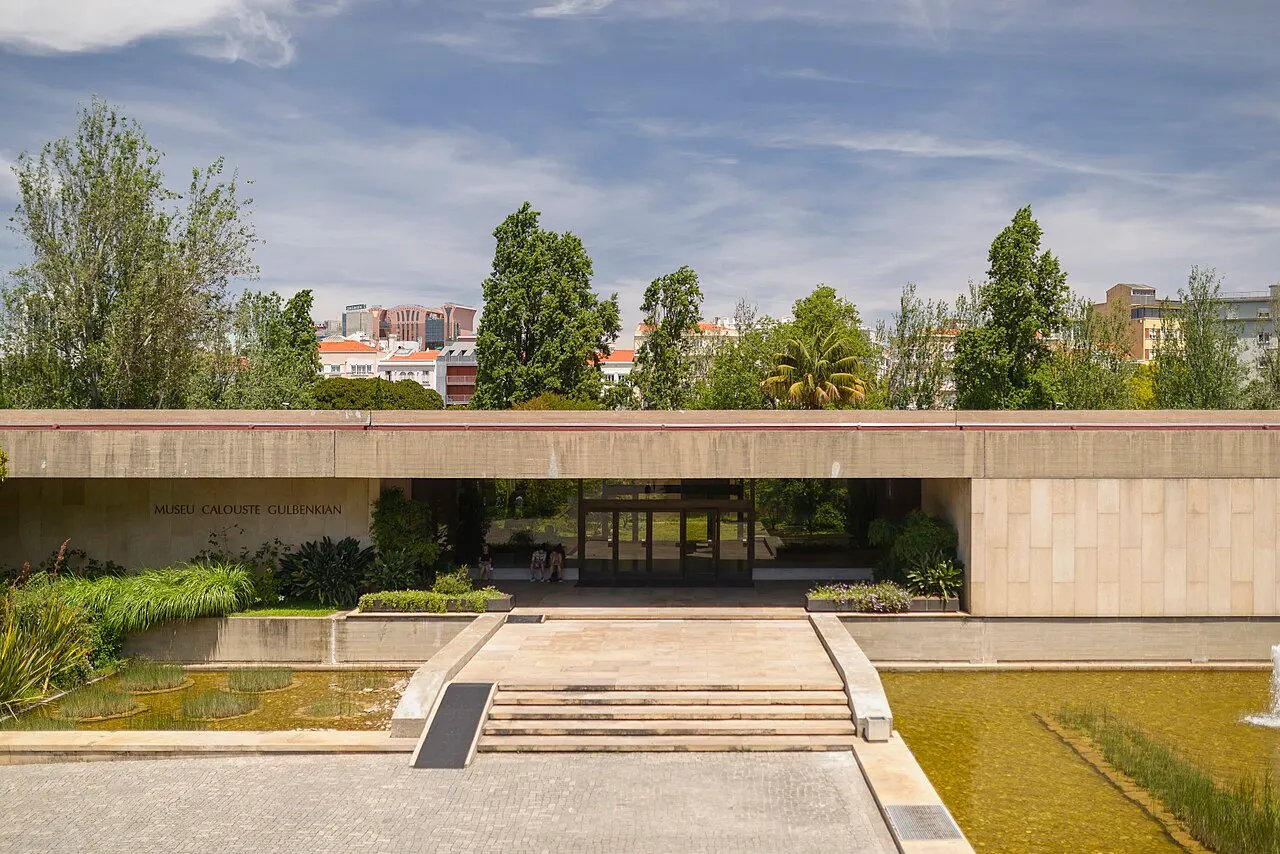 Entrada do Museu Calouste Gulbenkian, com a laje de concreto entre dois espelhos de água e as árvores atrás.