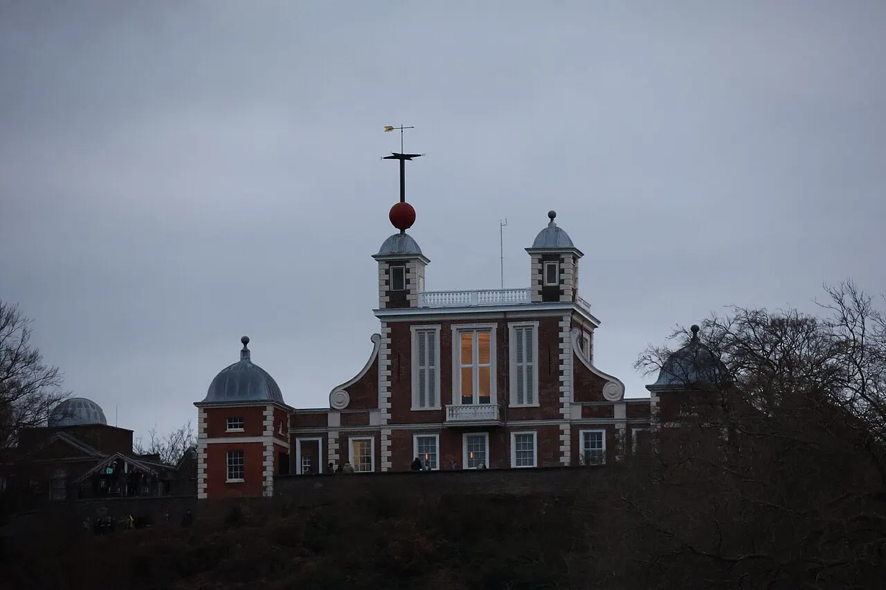 Casa Flamsteed, o prédio de tijolo do Observatório Real de Greenwich, com a bola do tempo no alto, ao entardecer.