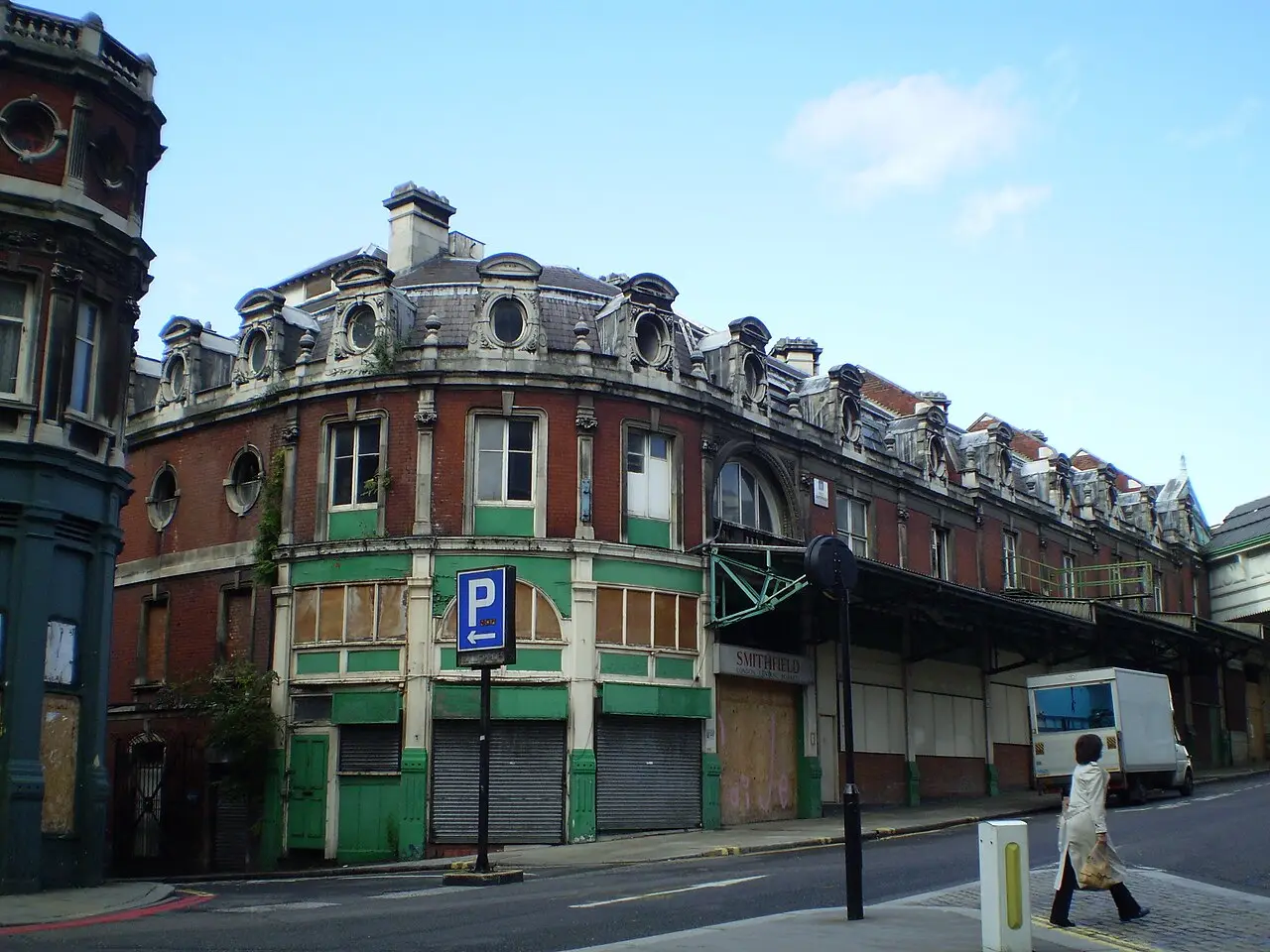 Edifício de esquina do antigo mercado de Smithfield, com janelas tapadas, cobertura de metal e rua em primeiro plano.