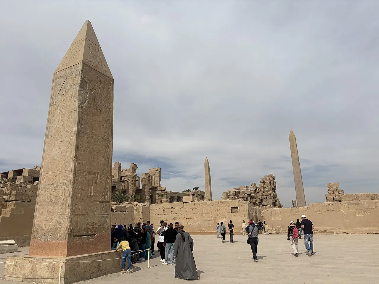 Obelisco de granito no complexo de Karnak, em Luxor, com visitantes pequenos ao pé.