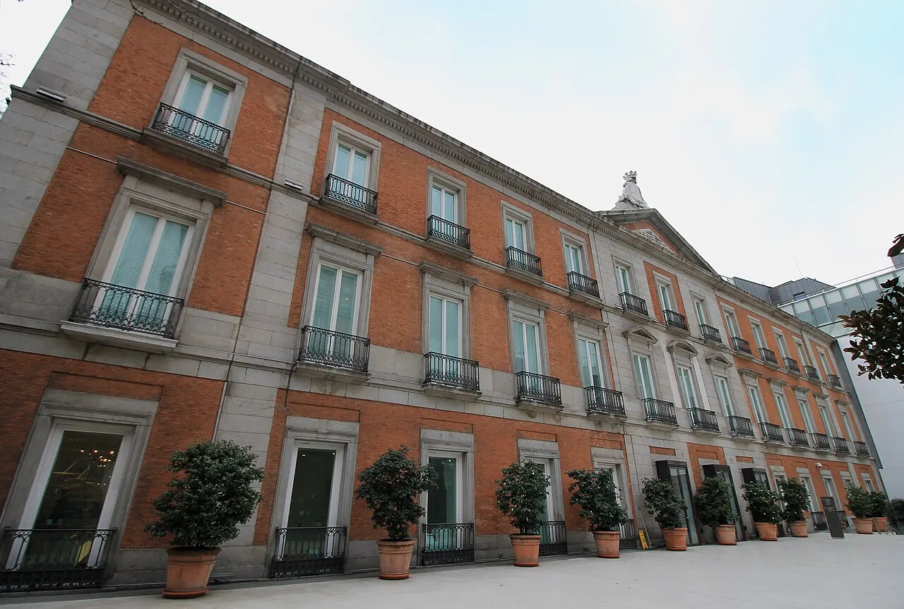 Fachada de tijolo do Museu Thyssen-Bornemisza, com varandas e vasos no pátio.