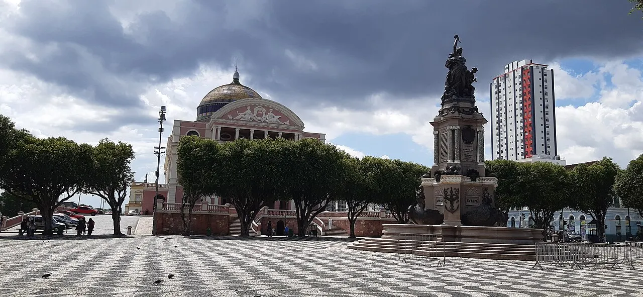 Monumento de pedra e bronze no centro do Largo de São Sebastião, em Manaus, sobre o calçadão ondulado.