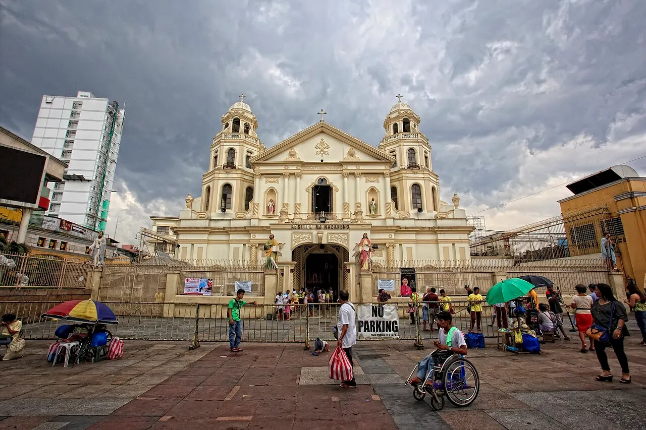 Fachada da Basílica do Nazareno Negro, em Quiapo, sob céu carregado, com pessoas na praça à frente.