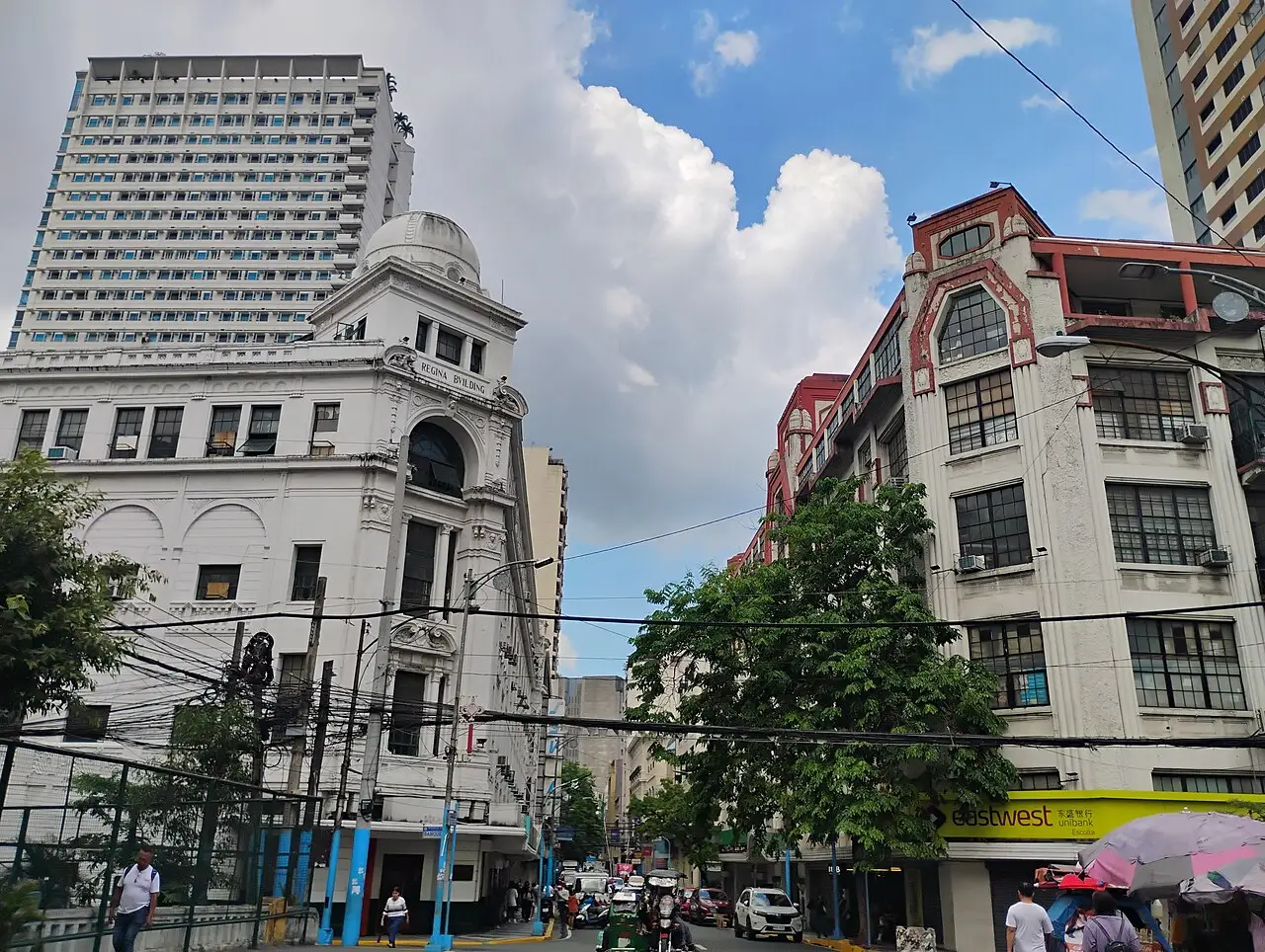 Esquina da rua Escolta, com um prédio branco de cúpula baixa, um edifício vermelho ao lado e fios sobre a calçada.