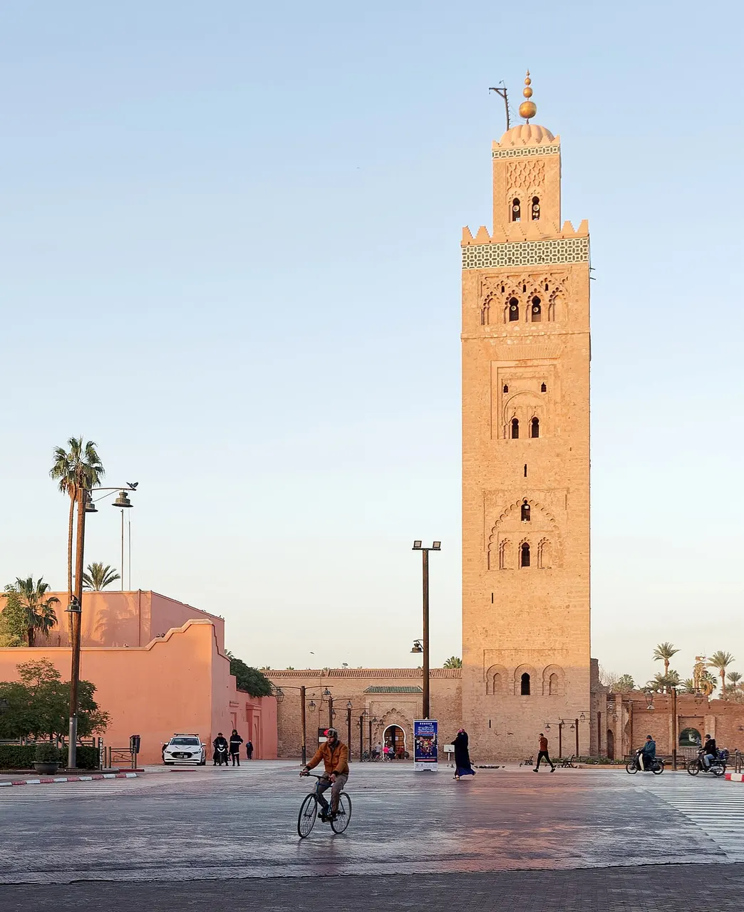Minarete de pedra ocre da Mesquita Koutoubia, em Marraquexe, visto da praça sob céu azul.