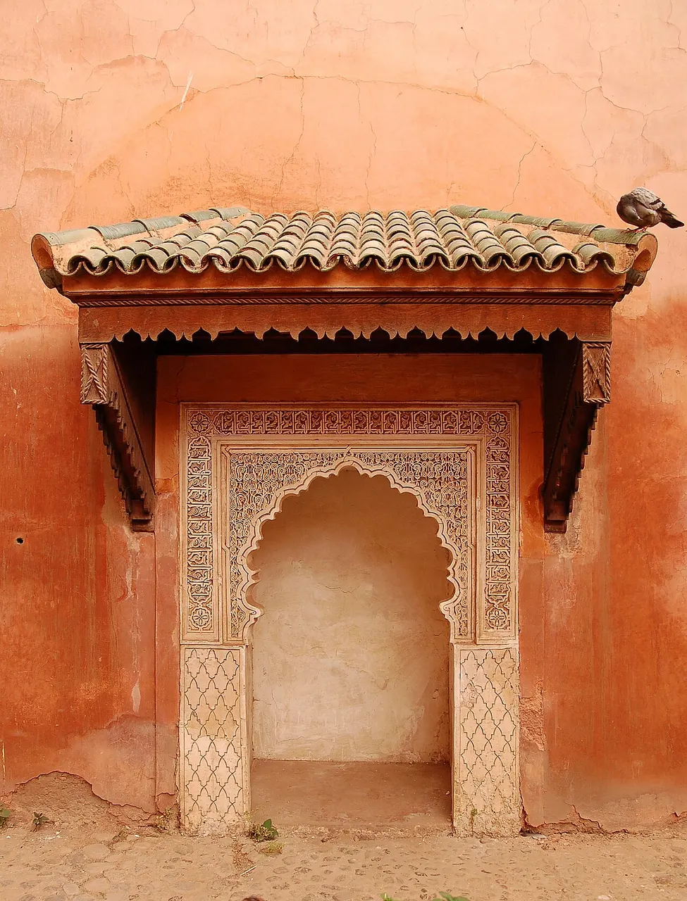 Pavilhão de arco e telhado de telhas verdes nos Túmulos Saadianos, em Marraquexe, com paredes de estuque.