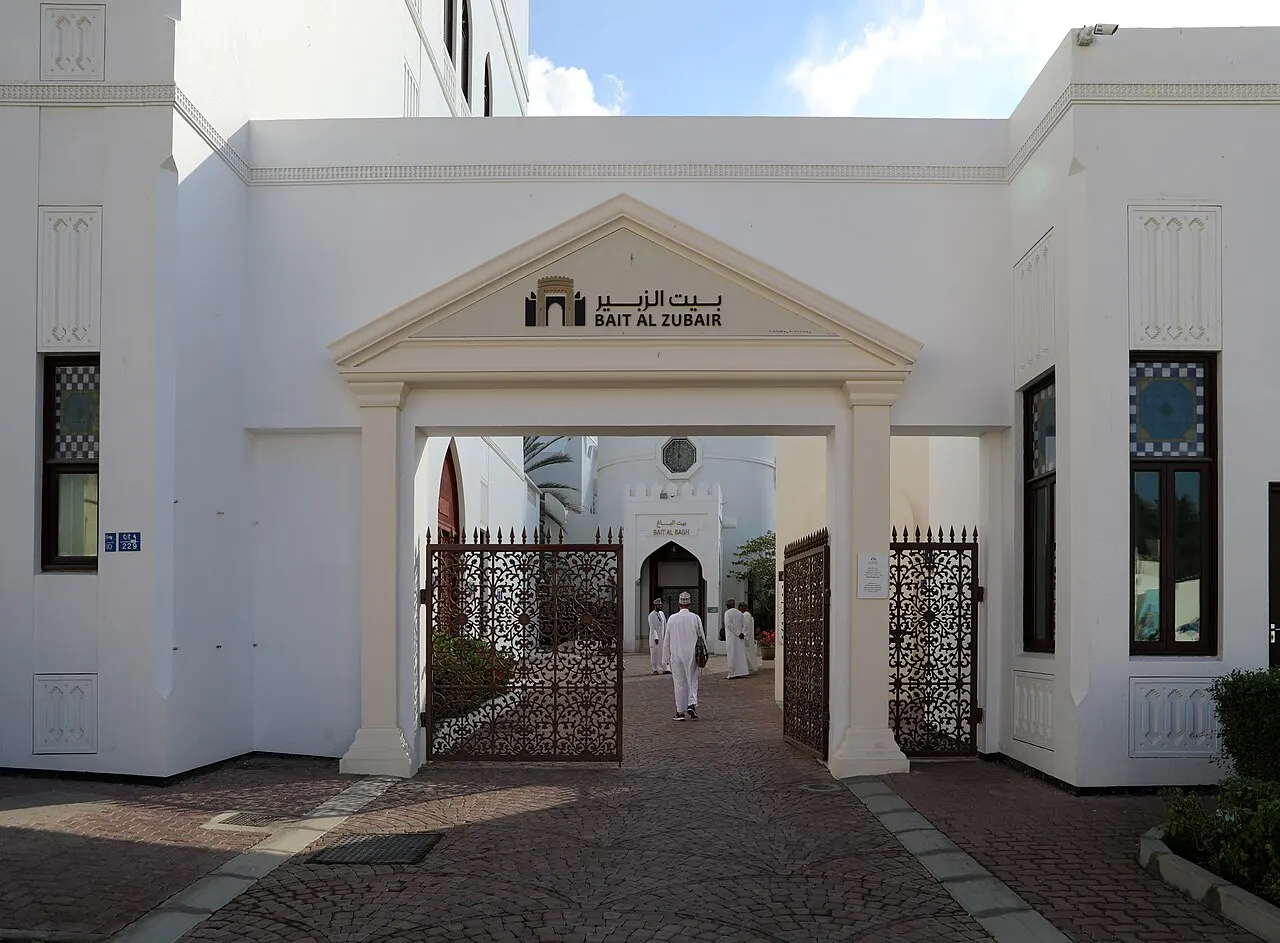 A white portico with a triangular pediment and the museum's name, open wrought-iron gates and a stone path leading to the inner courtyard.