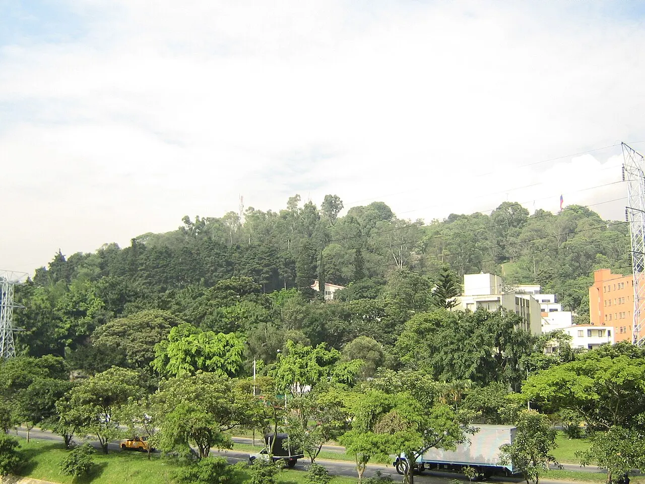 Encosta arborizada do Cerro Nutibara, com edifícios da cidade aparecendo entre as árvores ao fundo.