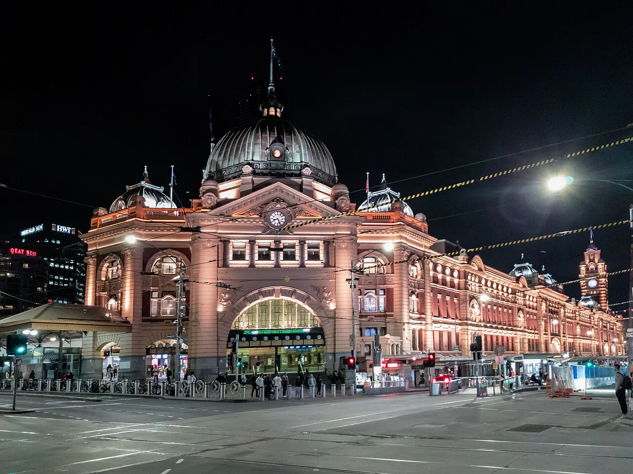 A estação Flinders Street iluminada à noite, com a cúpula sobre a entrada.