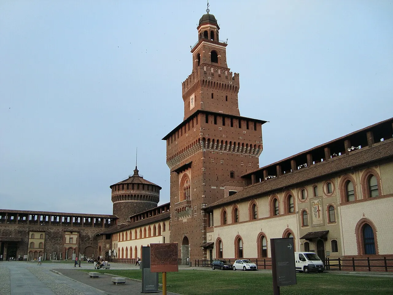 Torre central e muralha de tijolos do Castello Sforzesco, vistas do lado de fora, sob céu claro.