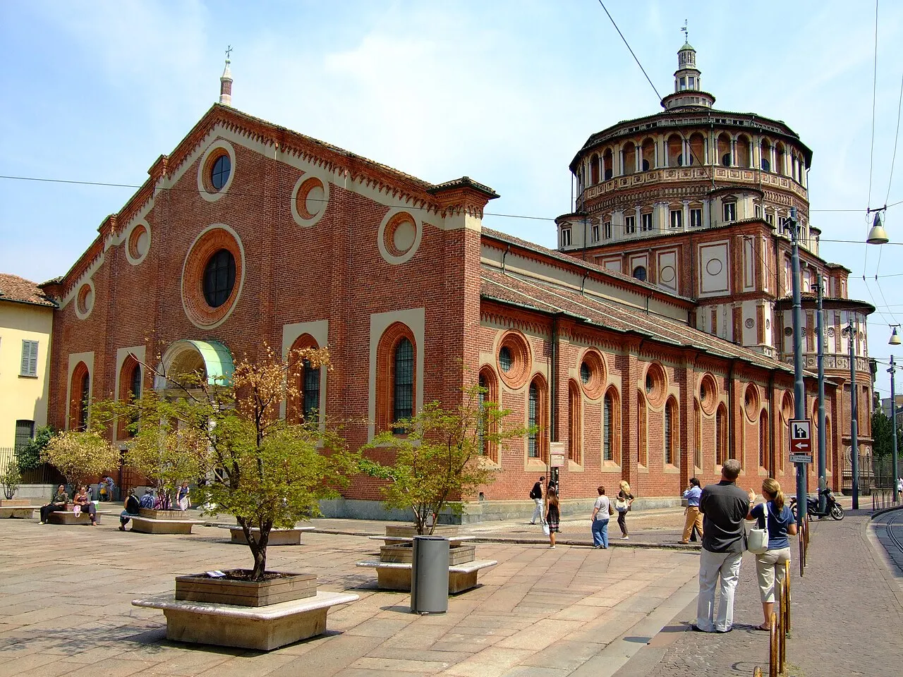 Igreja de Santa Maria delle Grazie, em Milão, de tijolo, com a tribuna redonda, sob céu azul.