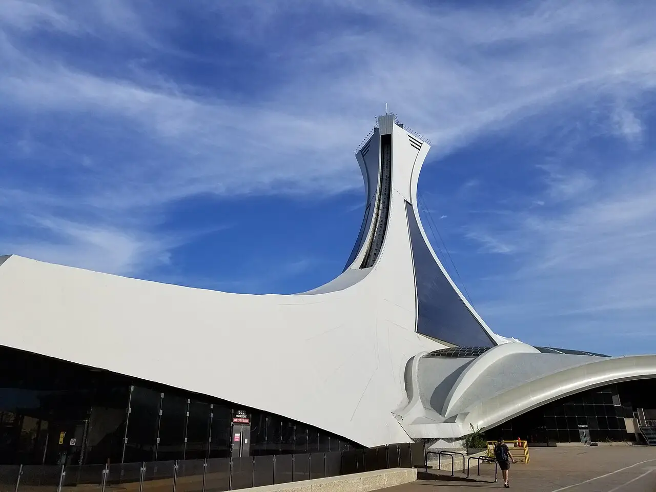 Cobertura branca curva com um mastro, vista de fora, sob céu azul.