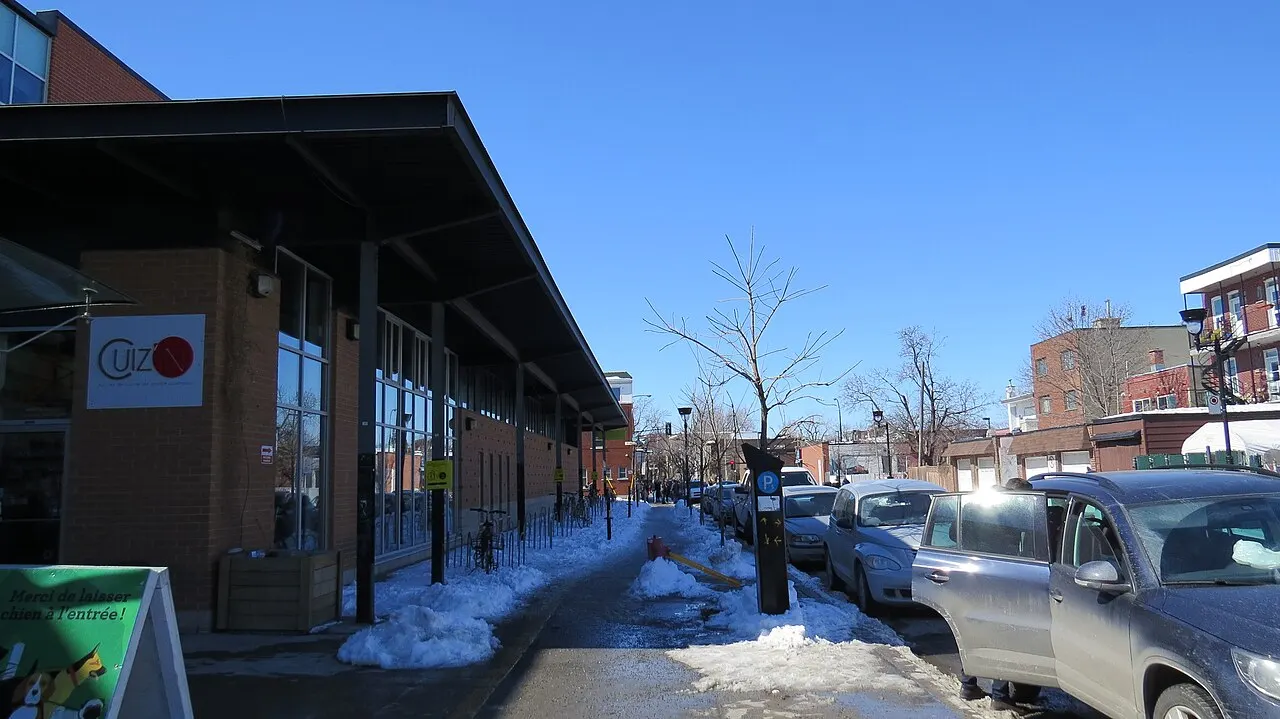 Pavilhões de tijolo com telhados inclinados do Marché Jean-Talon, em uma rua com neve nas calçadas.