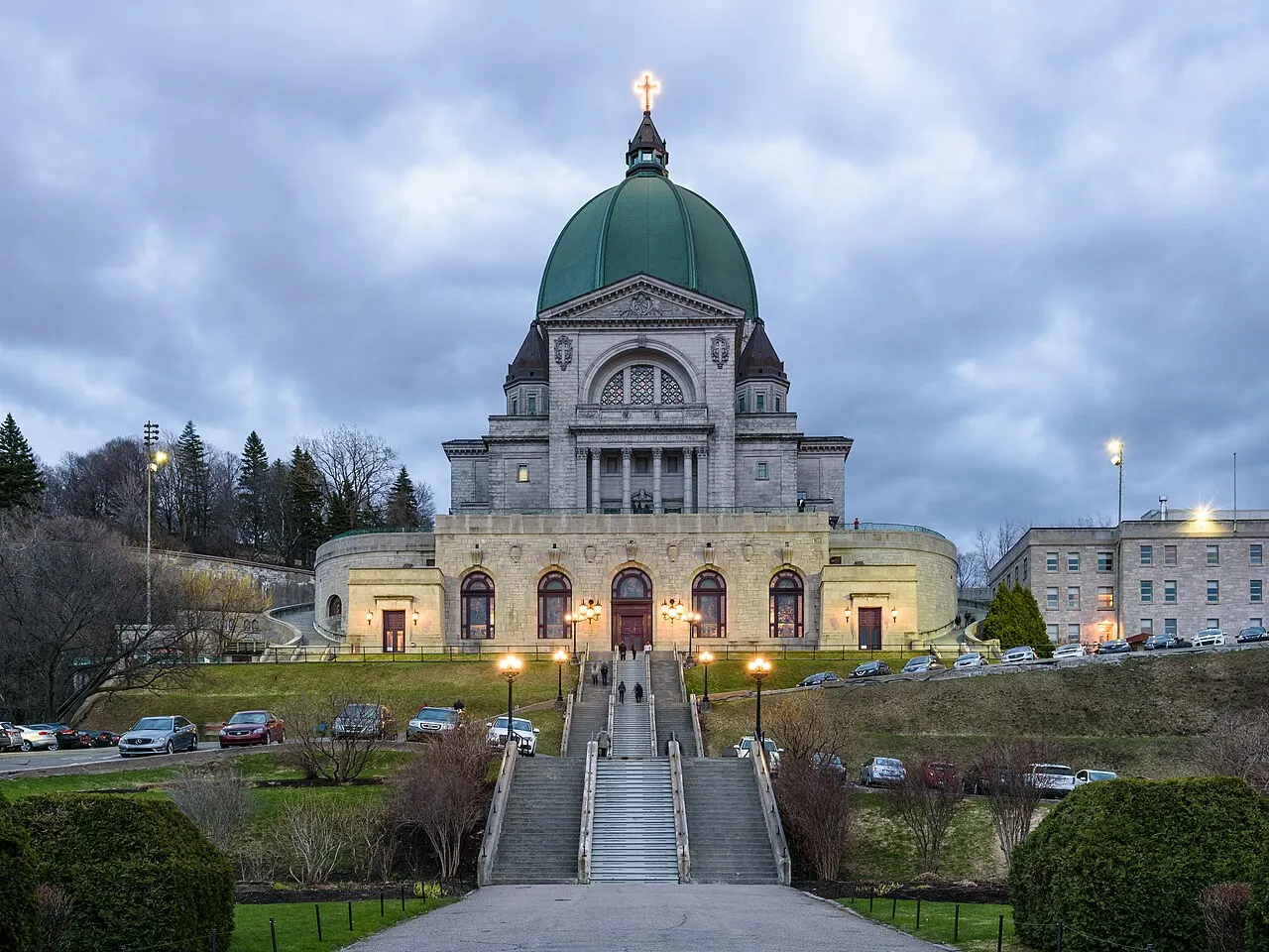 Oratório de São José, em Montreal, com a grande cúpula verde sobre a fachada de pedra, ao entardecer.