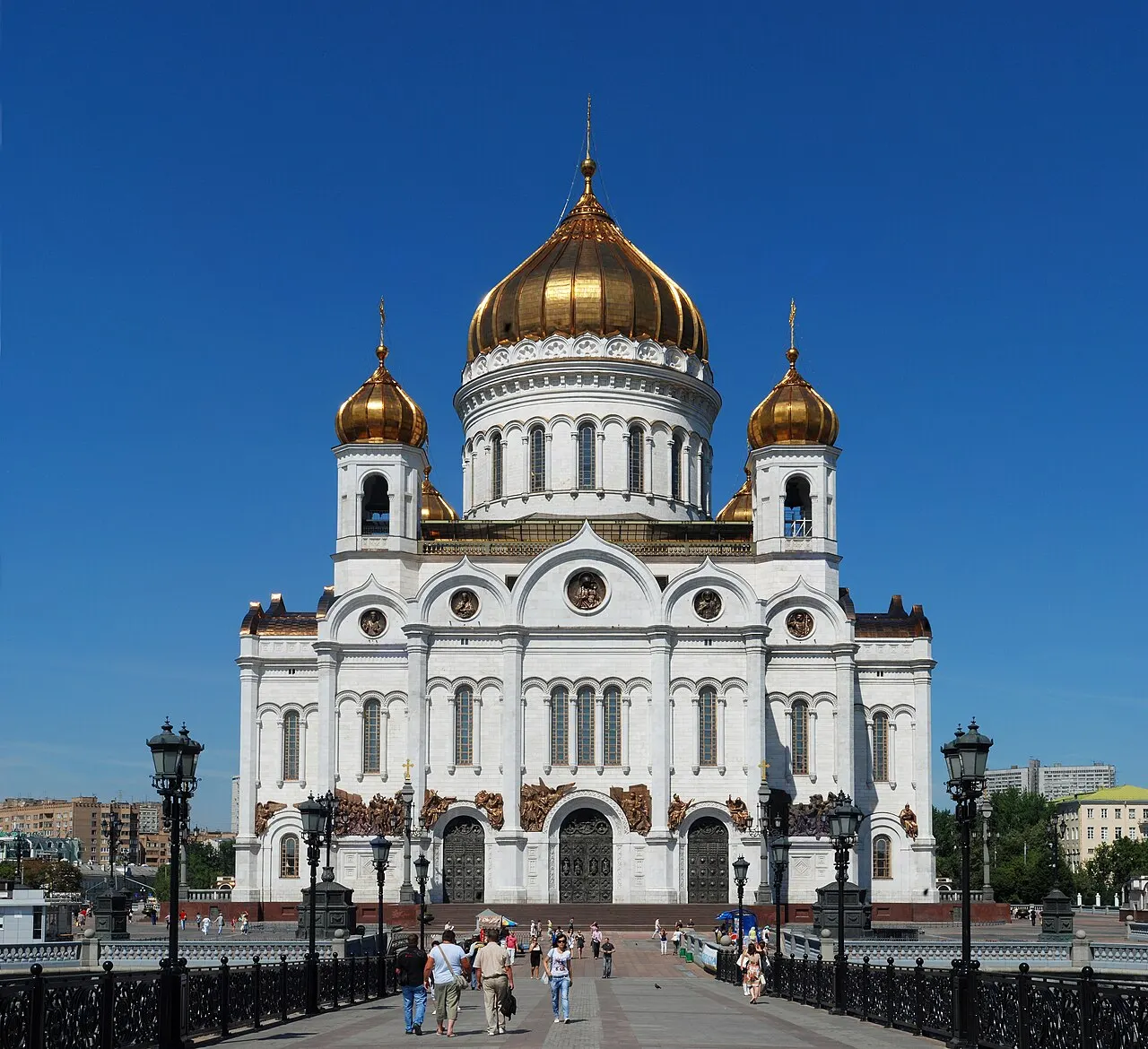 Catedral de Cristo Salvador, em Moscou, branca com cúpulas douradas, vista da ponte sob céu azul.