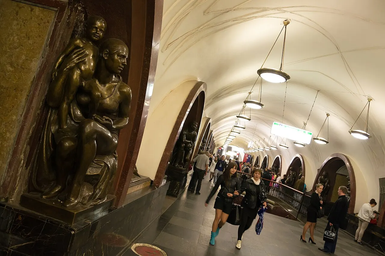 Statue en bronze sous une arche de la station de métro Plochtchad Revolioutsii, à Moscou, avec des voyageurs dans le hall.