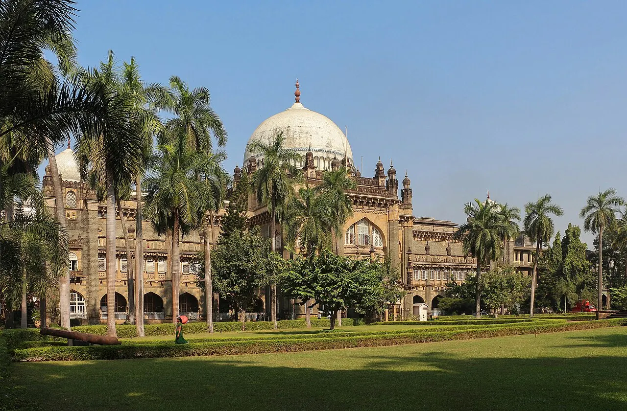 O museu Chhatrapati Shivaji Maharaj Vastu Sangrahalaya, de arquitetura indo-sarracênica, com grande cúpula central, fachada de pedra e um jardim em frente.