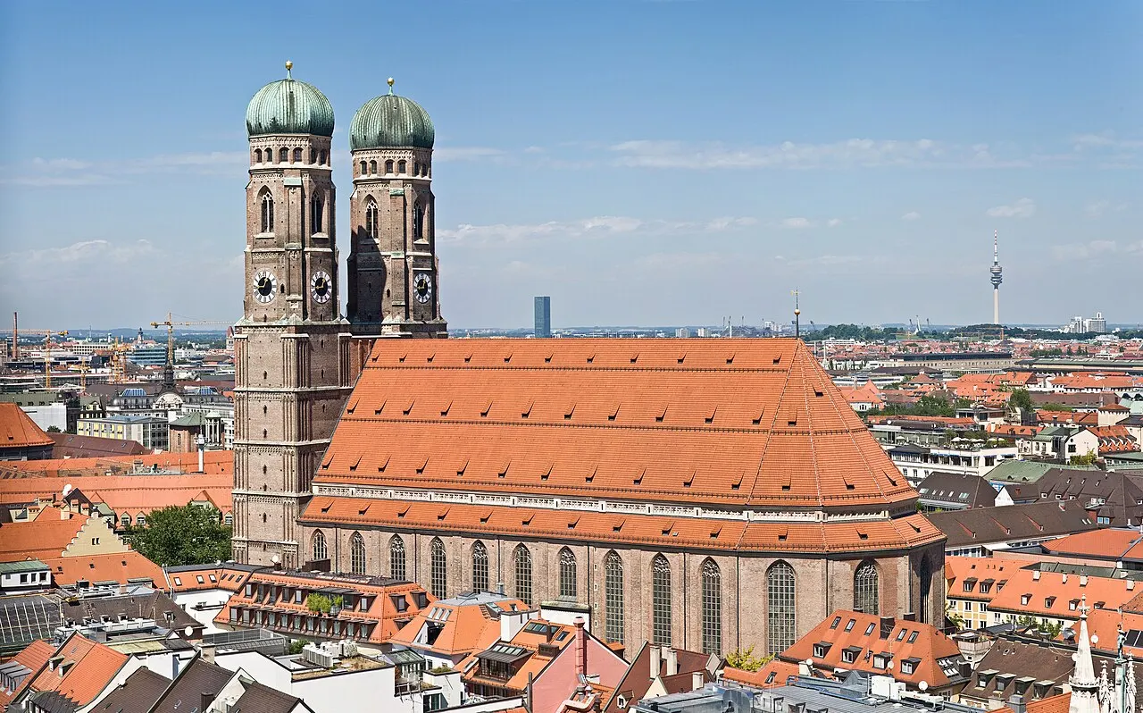 Frauenkirche de Munique vista do alto, com as duas torres de cúpula verde e o grande telhado vermelho.
