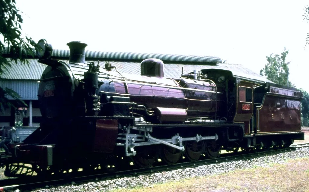 Locomotiva a vapor de cor escura exposta ao ar livre no Museu Ferroviário de Nairóbi.