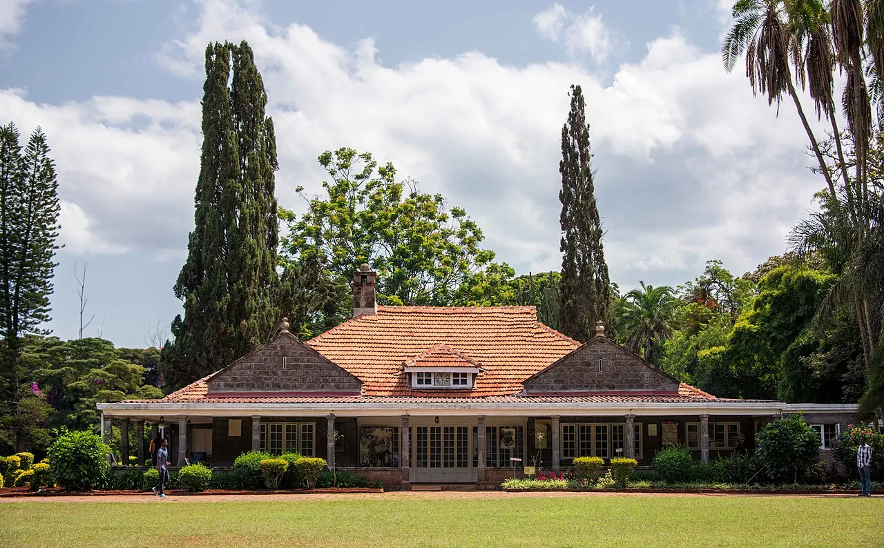 Casa de Karen Blixen, em Nairóbi, casa baixa de pedra com telhado de telhas, entre árvores.
