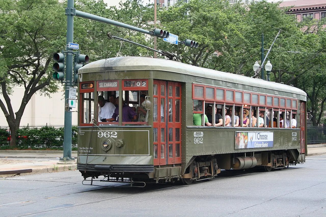 Bonde verde da linha St. Charles, em Nova Orleans, parado na rua sob as árvores.