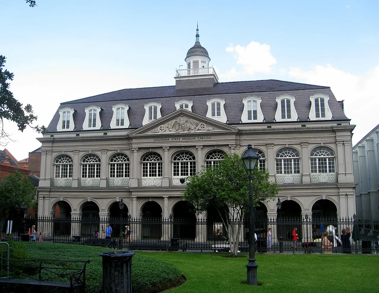 Fachada do Cabildo, com telhado de mansarda e cúpula, vista do gramado da Jackson Square.