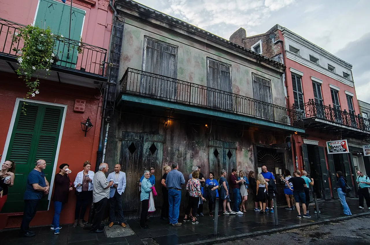 Fila de visitantes na calçada diante do Preservation Hall, em um casarão do Bairro Francês com balcões de ferro.