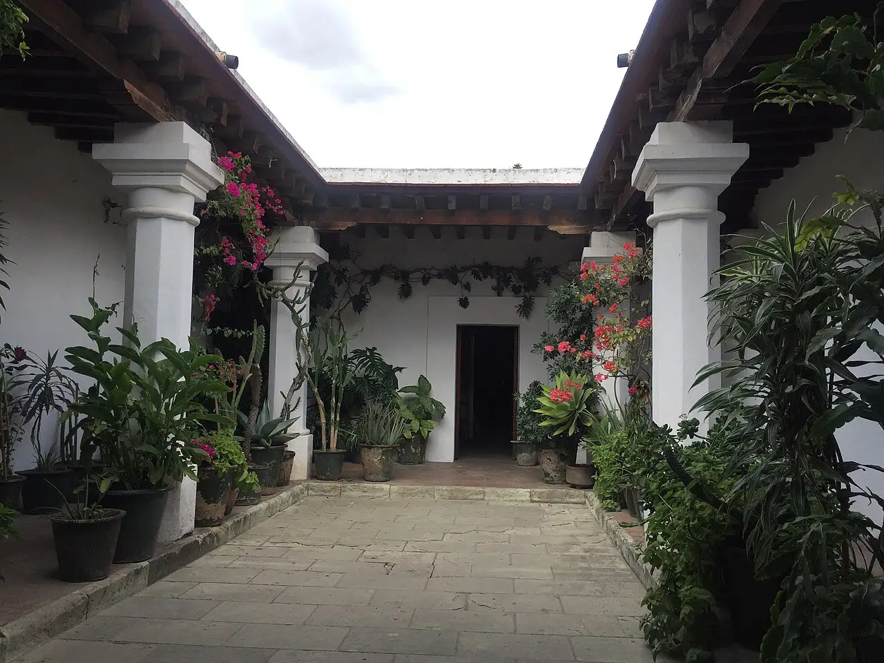Arcada branca com colunas e plantas, no pátio central do instituto.