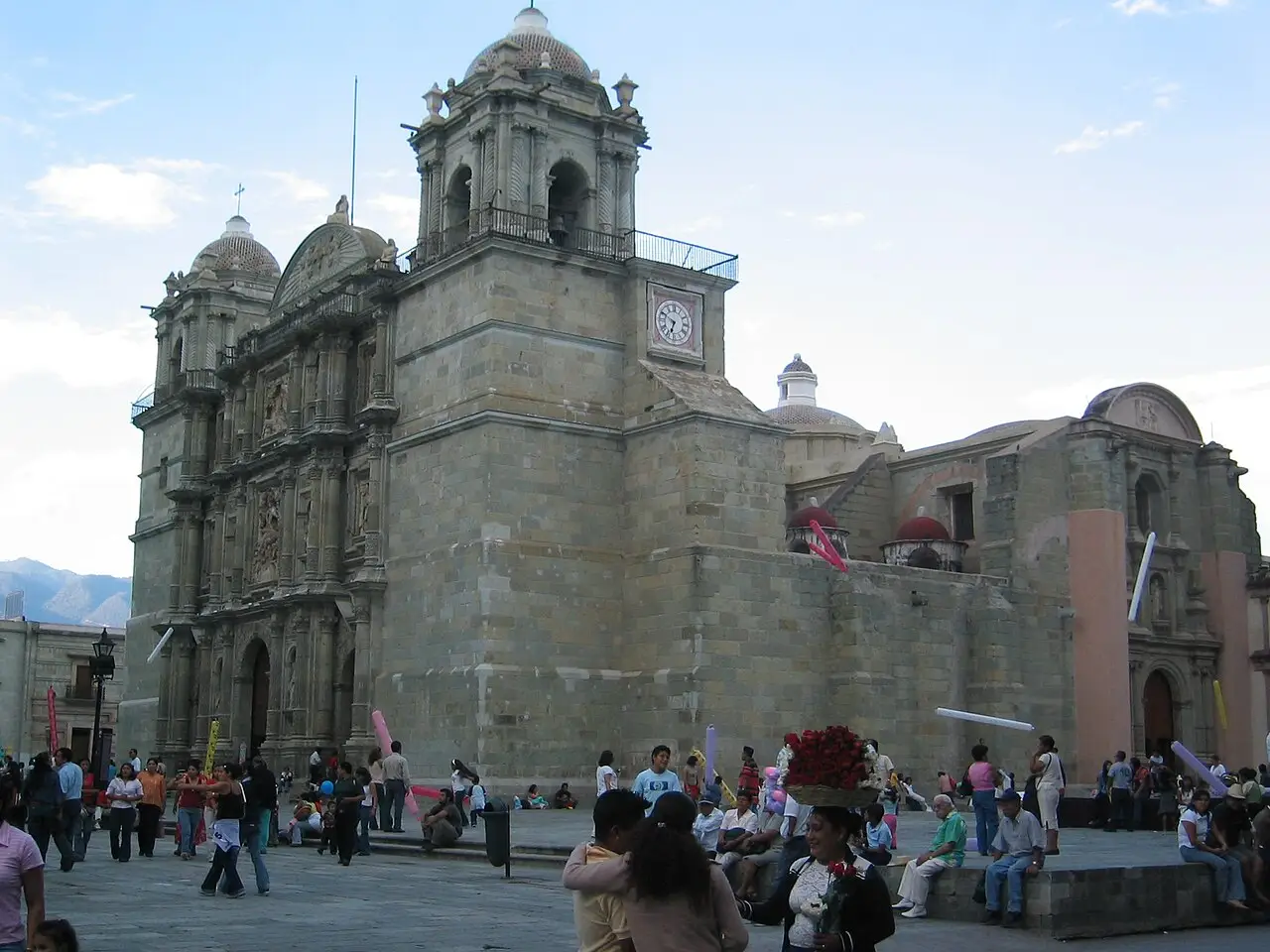 Fachada de pedra da catedral, com a praça e pessoas na frente.