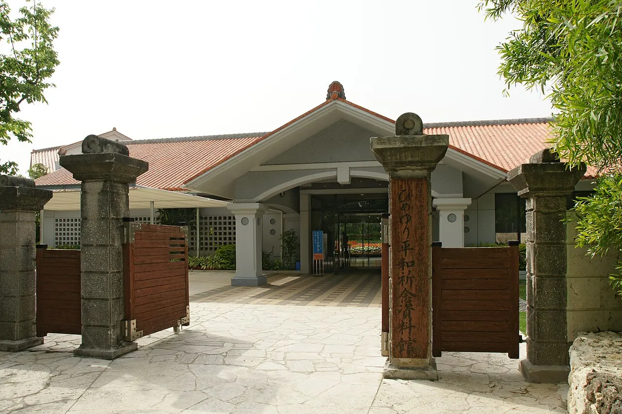The entrance of the Himeyuri Peace Museum, with stone pillars at the gate and the building with a reddish tiled roof behind.