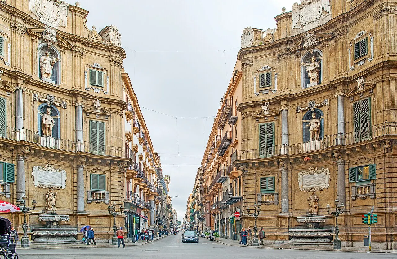 Duas das quatro fachadas barrocas curvas dos Quattro Canti, com estátuas em nichos, e a rua que segue entre elas.