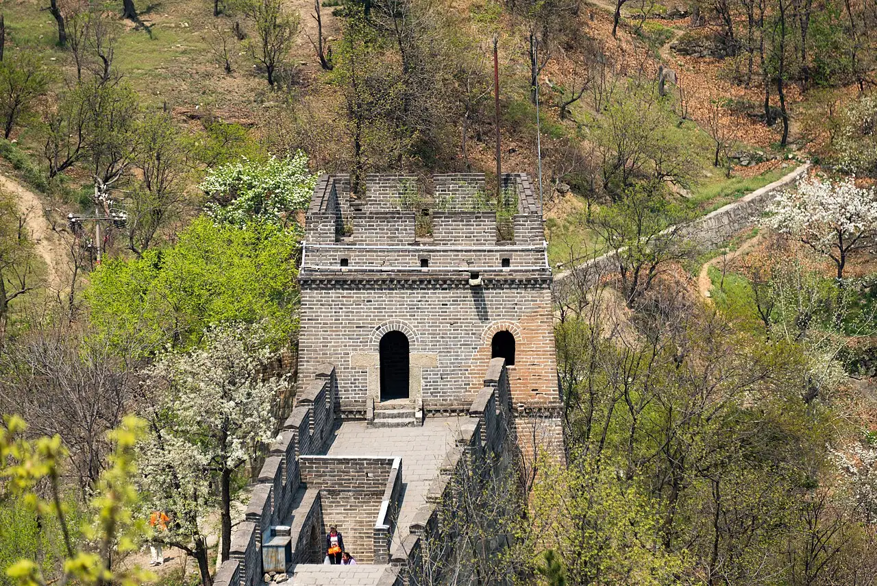 Torre de vigia de pedra cinza com porta em arco e ameias, sobre o caminho de ronda da muralha.