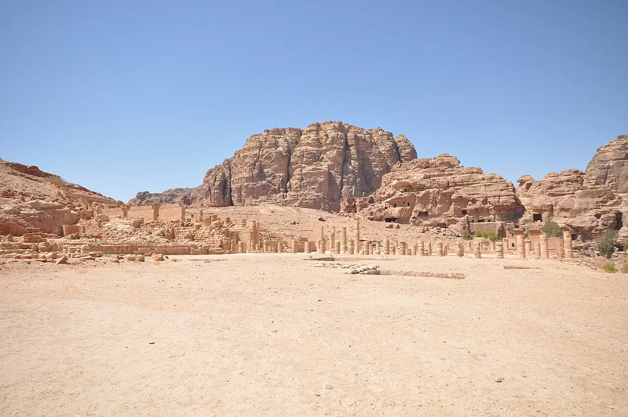 Planície de areia diante de rochedos em Petra, com fileira de colunas ao longe, no sítio da Igreja Bizantina.