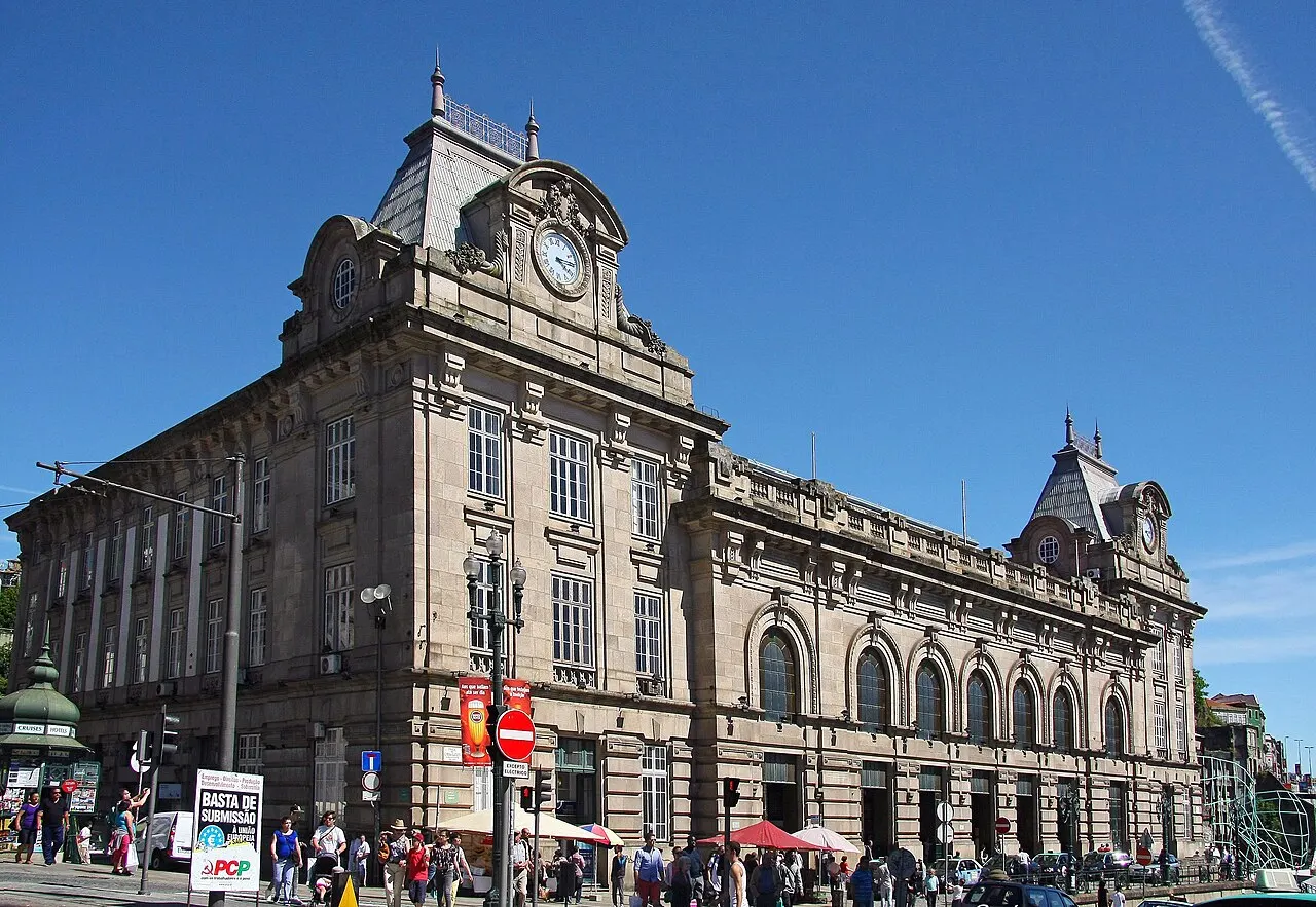 Estação de São Bento, no Porto, prédio de pedra com mansardas e relógio, sob céu azul.